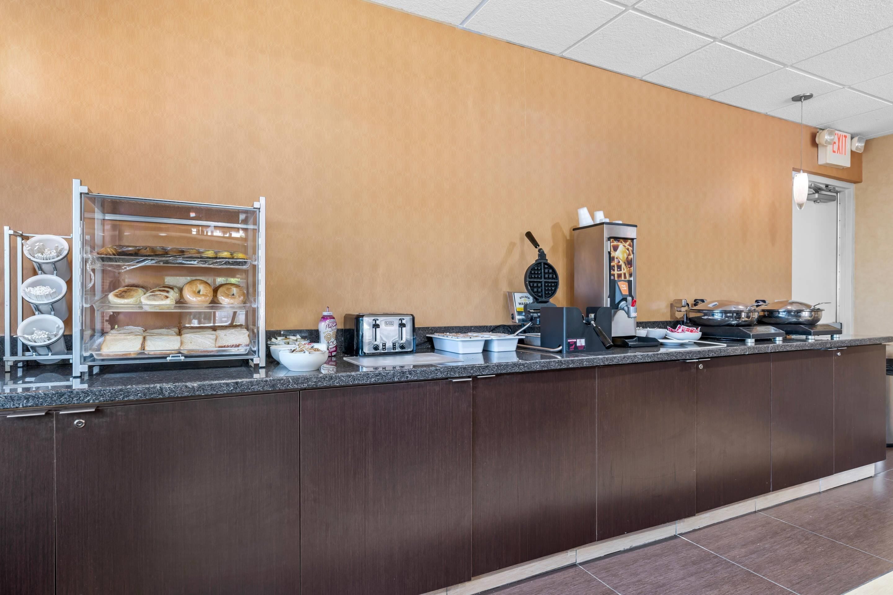 A kitchen area with a bread display, toaster, waffle maker, and various cooking utensils.