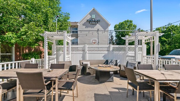 A MainStay Suites outdoor patio with wicker furniture, a fire pit, and a white fence. - MainStay Suites Appleton Airport - Fox River Mall Area (Appleton)