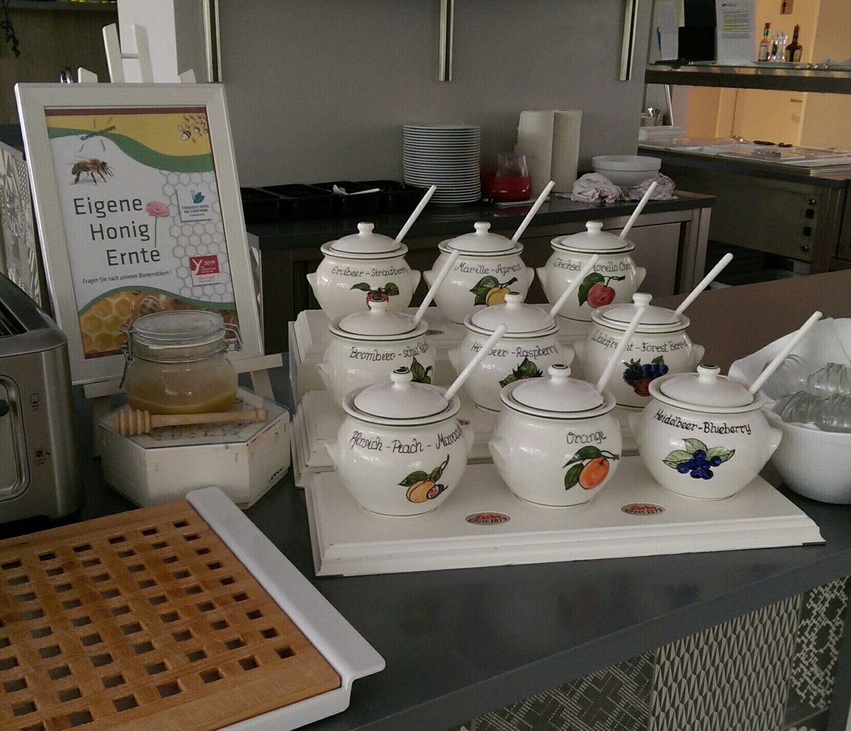 A buffet setup with various fruit preserves in labeled containers.
