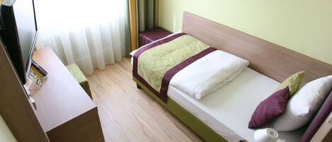 Una habitación de hotel con cama, escritorio, teléfono y televisión.
