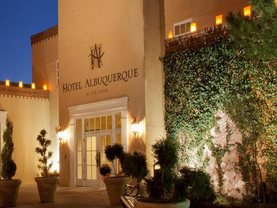 The exterior of Hotel Albuquerque at Old Town, featuring a large entrance with a double door, potted plants, and a wall covered in ivy.