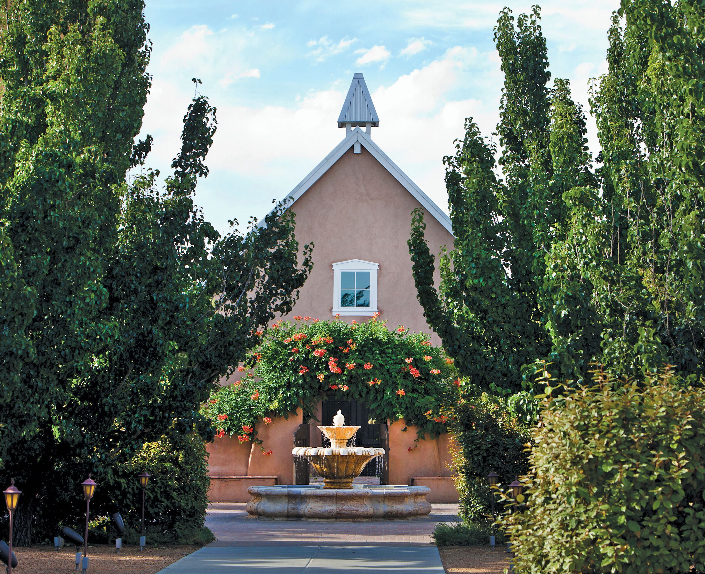 Un bâtiment doté d’un toit triangulaire, d’une petite fenêtre et d’une fontaine au centre.