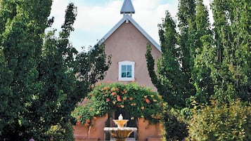 Un bâtiment doté d’un toit triangulaire, d’une petite fenêtre et d’une fontaine au centre.