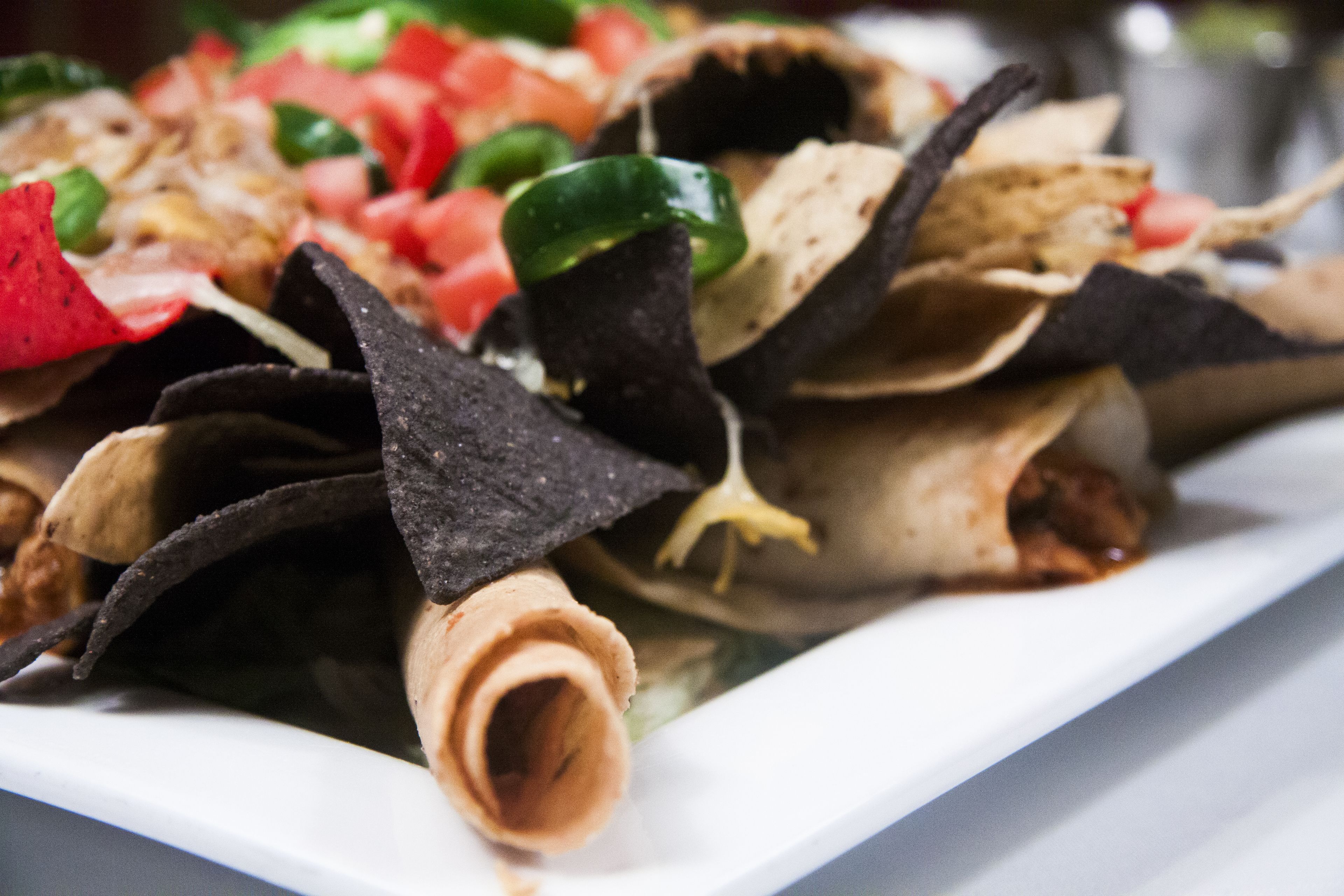 A plate of nachos with tortilla chips, cheese, and toppings.