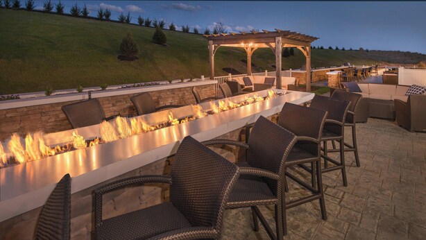 Un patio al aire libre con una mesa larga, sillas y una chimenea.