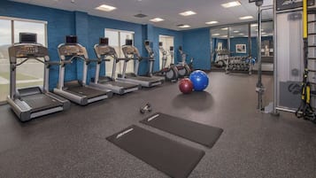 Un gimnasio con cintas de correr, elípticas y pelotas de ejercicios.