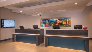 Una zona de recepción con dos mostradores, un gran mapa digital y un cuadro en la pared.