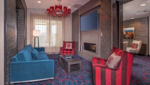 Una sala de estar moderna con un sofá azul, un sofá a rayas rojo y negro, una mesita de centro y una chimenea.