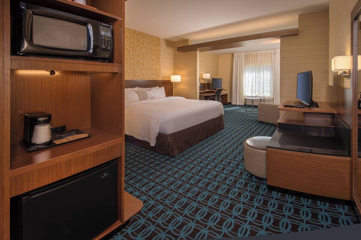 Une chambre d’hôtel équipée d’un lit, d’un bureau, d’une télévision, d’un four à micro-ondes et d’un réfrigérateur.