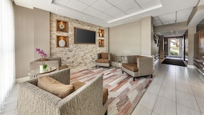 A modern living room with a stone accent wall, a flat-screen TV, and comfortable seating.