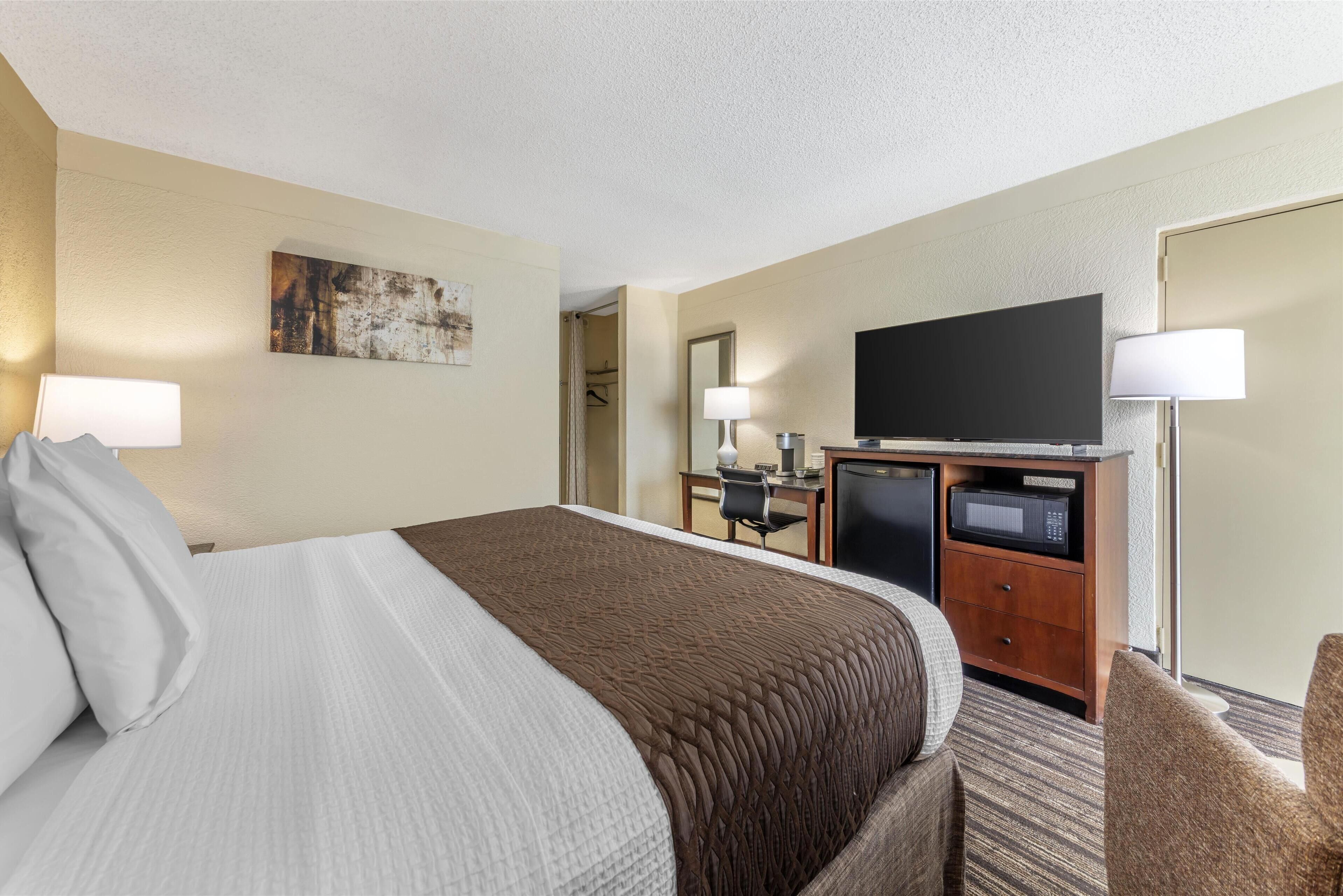 Hotelkamer met een groot bed, een bureau met een computer, een flatscreen televisie en een magnetron.