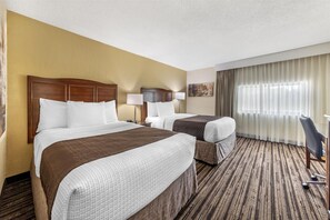 A hotel room with two beds, a large window with curtains, a desk, and a chair.