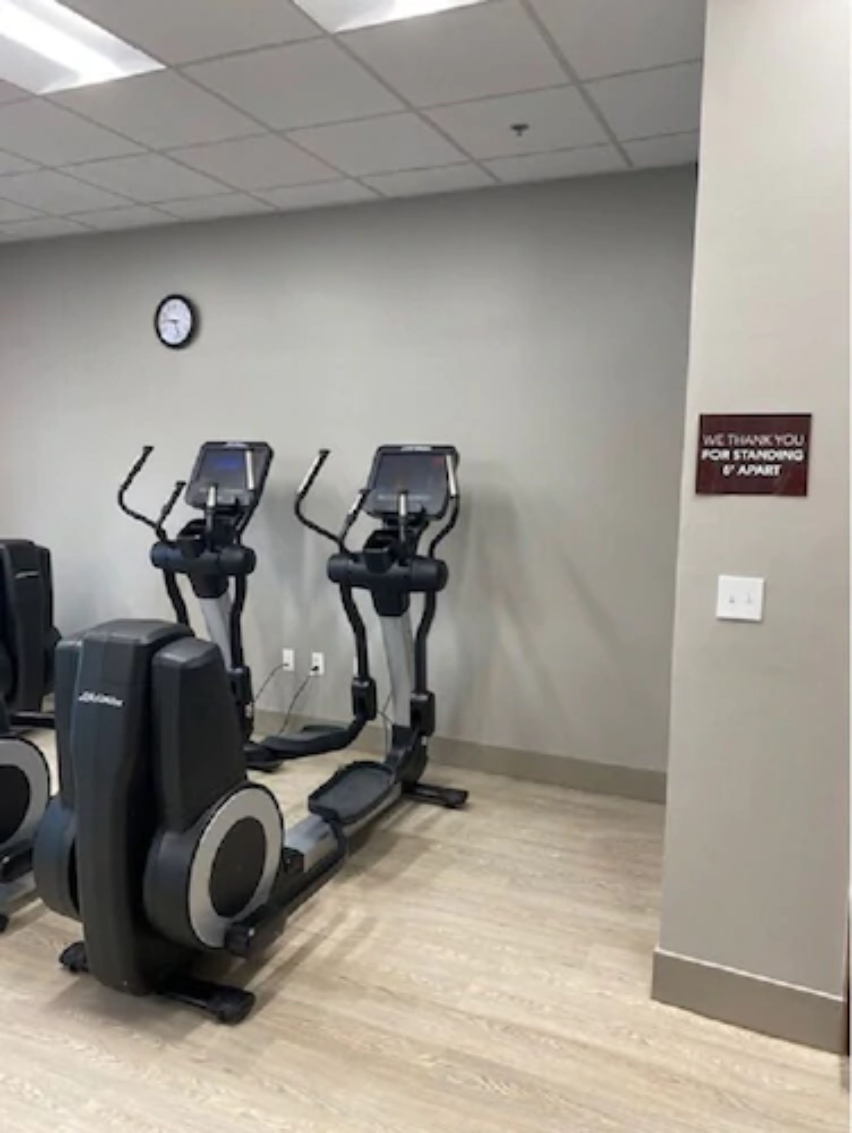 Un gimnasio con dos cintas de correr y un reloj montado en la pared.