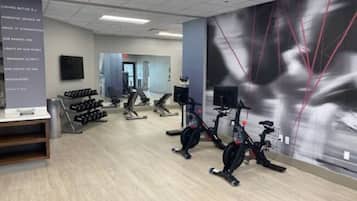 A gym with stationary bikes, treadmills, and dumbbells.