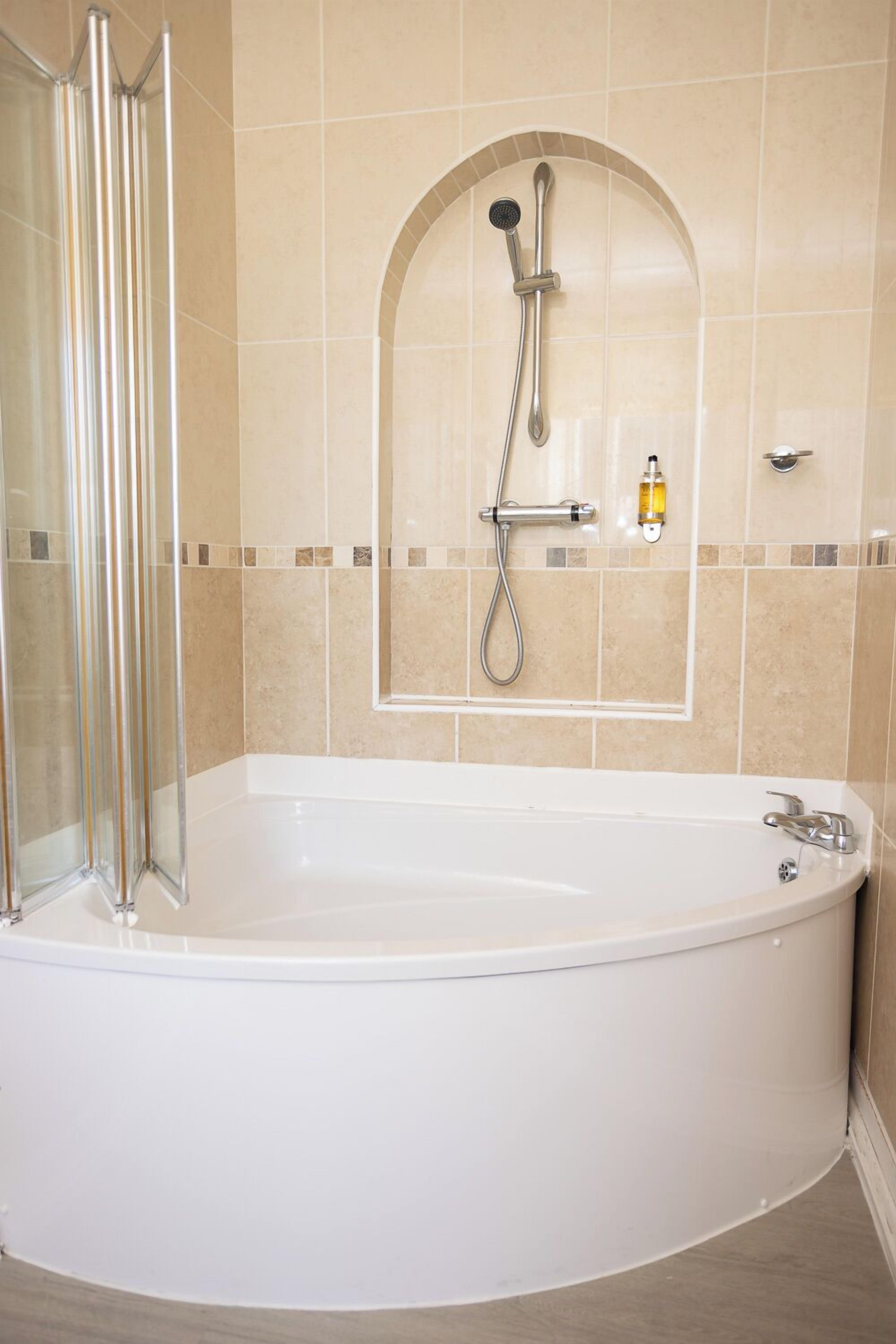A modern bathroom with a freestanding bathtub, a glass shower enclosure, and a showerhead mounted on the wall.