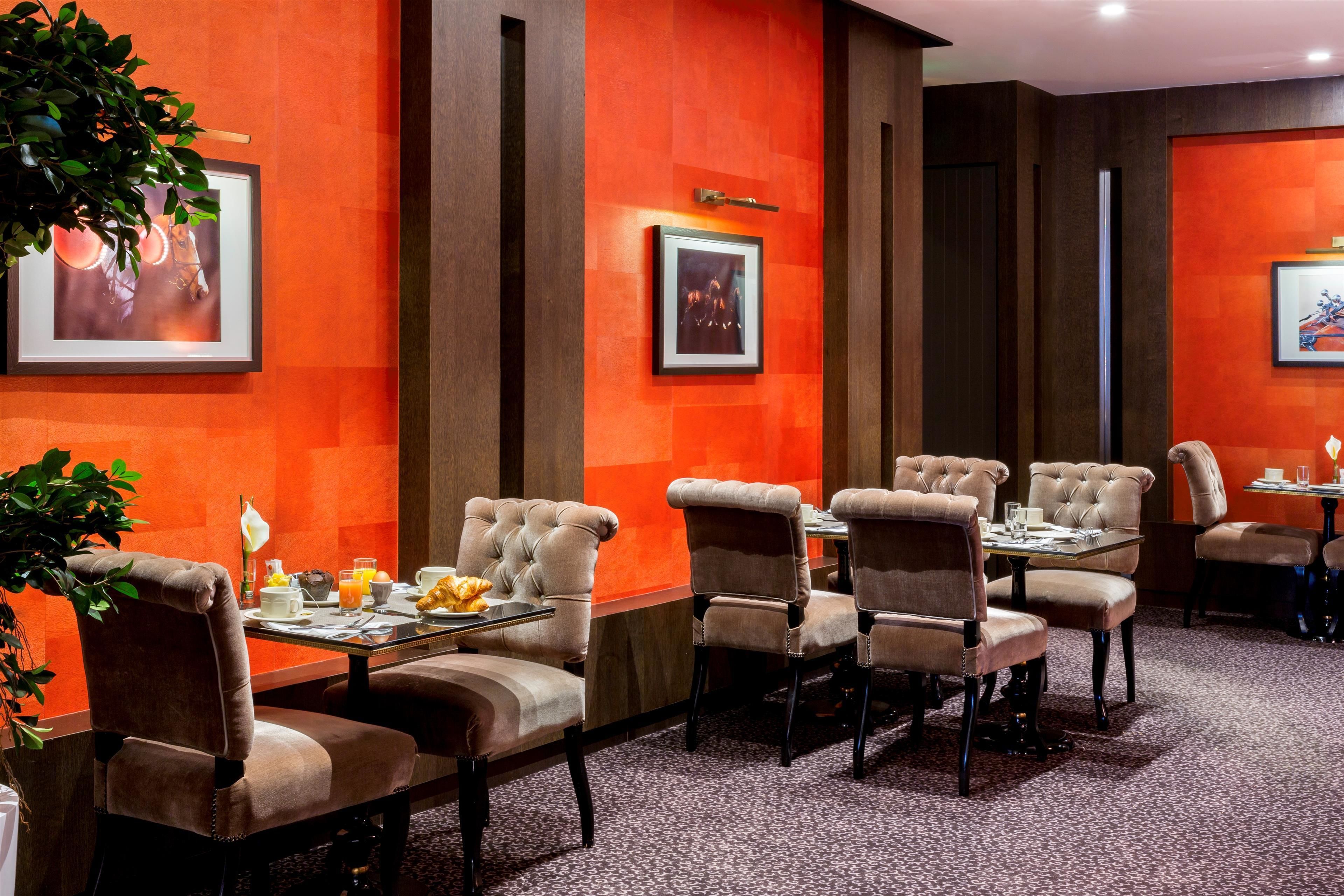 Un comedor con pared roja, cuadros enmarcados y un sistema de bufé.