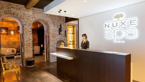 A reception area with a brick wall, a wooden reception desk, and a sign for 'NUXE spa Paris'. - Best Western Premier Hotel de la Poste & Spa (Troyes)