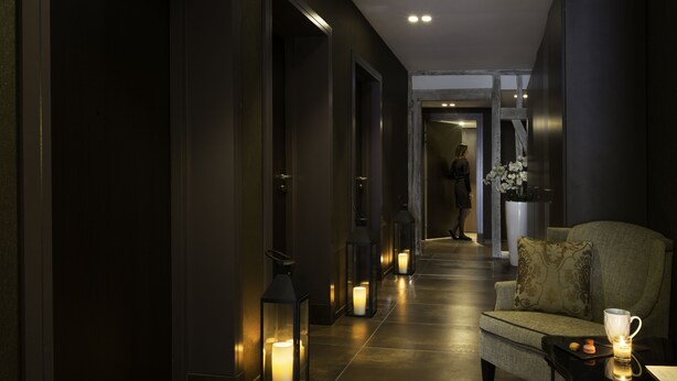 A dimly lit hallway with a sofa and a table with a candle and a cup. - Best Western Premier Hotel de la Poste & Spa (Troyes)