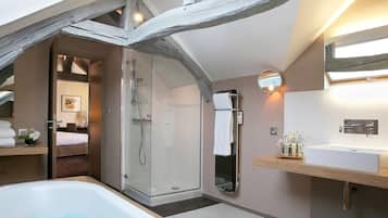 A modern bathroom with a glass-enclosed shower, a large bathtub, and a wooden vanity with a mirror.