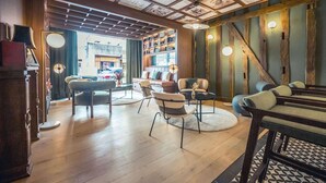 A cozy lounge area with wooden flooring, a sofa, chairs, and a bookshelf. - Best Western Premier Hotel de la Poste & Spa (Troyes)