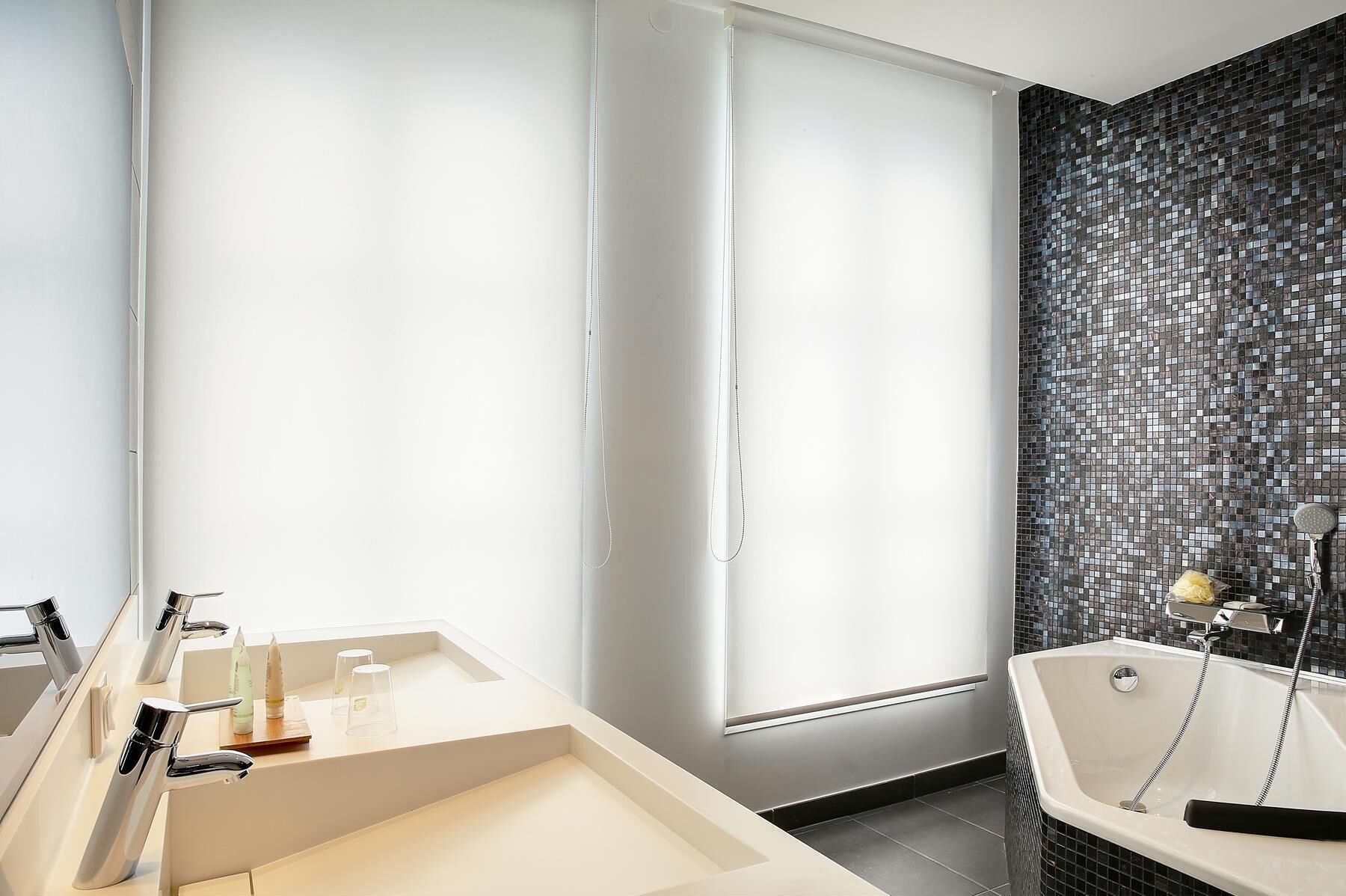 Une salle de bain moderne dotée d’une grande fenêtre, d’une baignoire et d’un meuble-lavabo avec un miroir et un évier.
