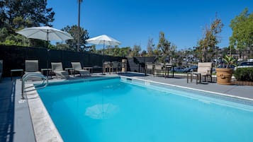 Een buitenzwembad, parasols bij het zwembad en ligstoelen