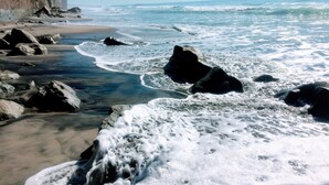 A rocky beach with waves crashing onto the shore and a cliff in the background. - Days Inn by Wyndham Encinitas Moonlight Beach (Encinitas)