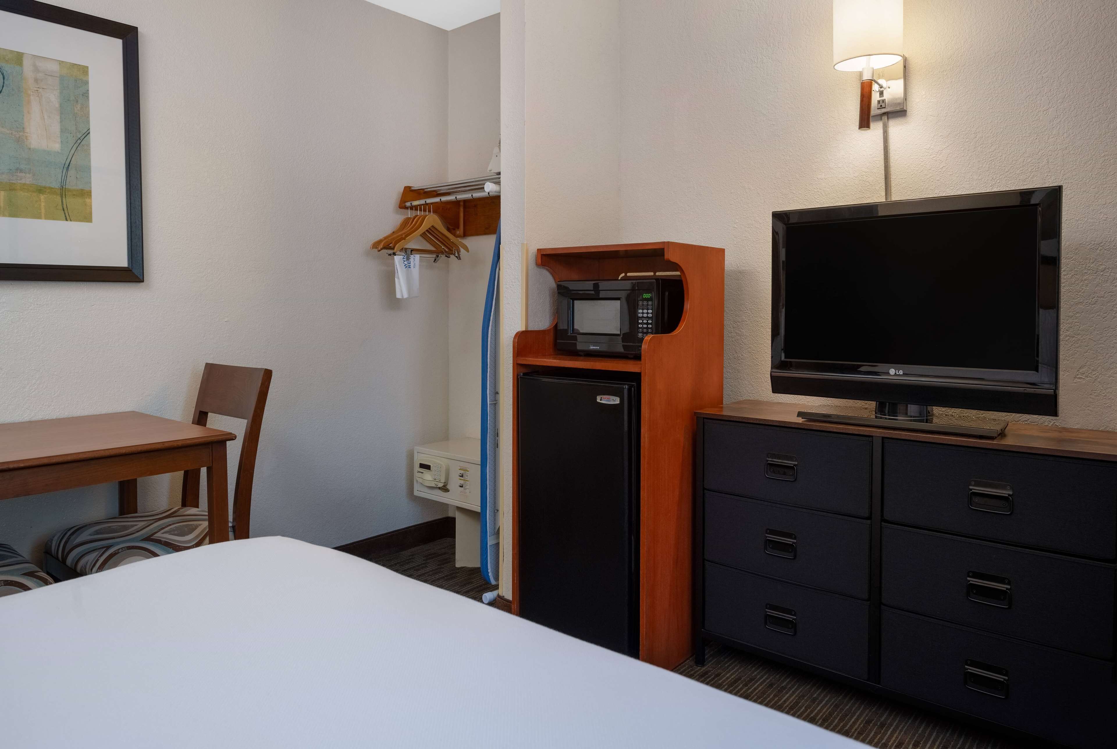 A hotel room with a bed, a desk, a television, a microwave, a mini-fridge, and a wardrobe.