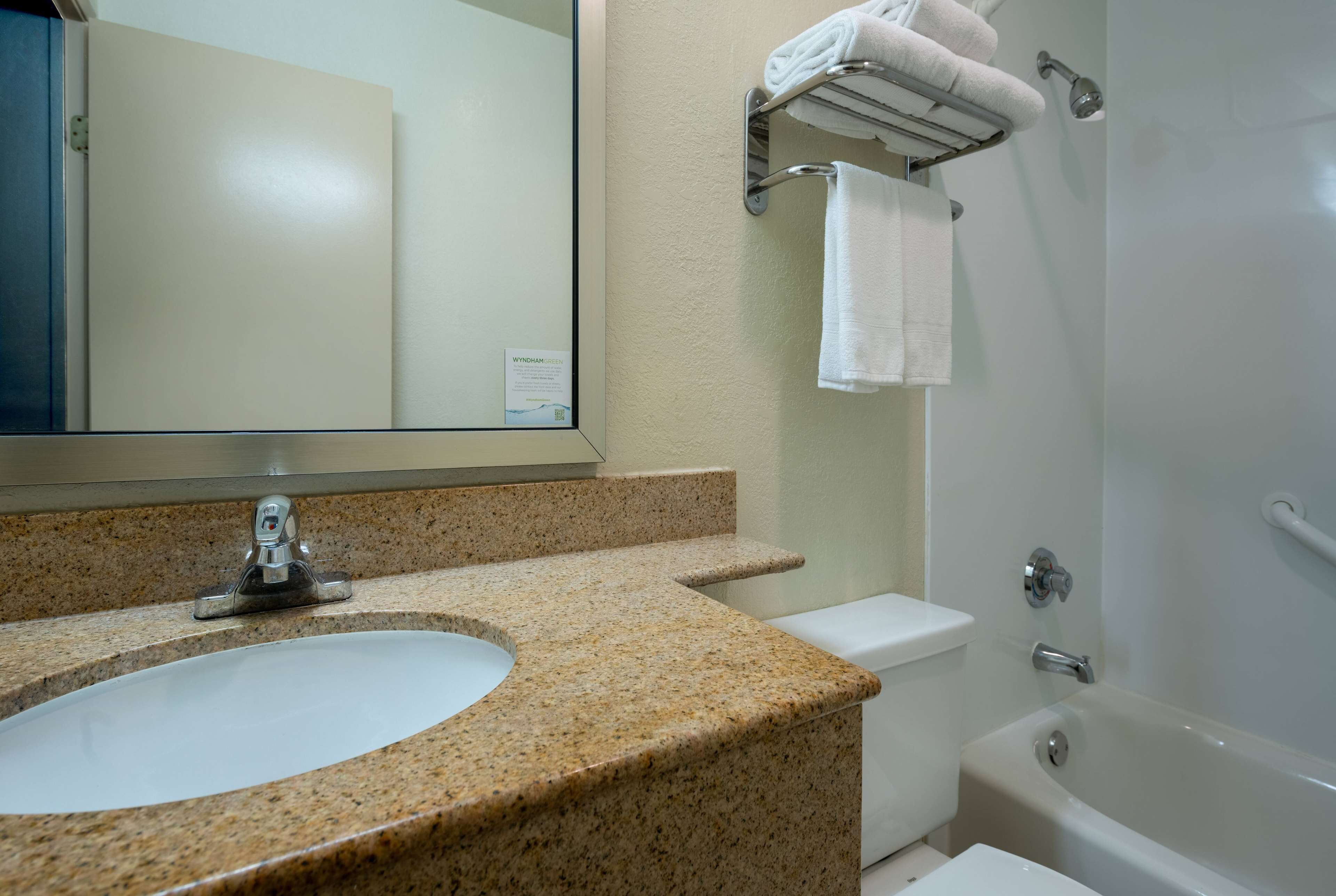 Un baño con lavamanos de encimera de granito, un espejo, un inodoro y una bañera.