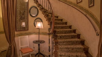 A grand staircase with ornate railings and a floral carpet.