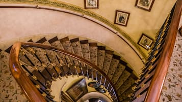 A grand spiral staircase with ornate railings and a carpeted floor.