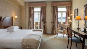 A hotel room with a large bed, a desk, a chair, and a view of the sea through the windows. - As Janelas Verdes Inn, a Lisbon Heritage Collection (Lisbon)