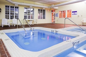 An indoor swimming pool with a tiled edge, a diving board, and a no diving sign on the wall. - Holiday Inn Express St. Ignace-Lake Front by IHG (St Ignace)