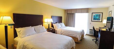 A hotel room with two beds, a desk with a computer, and a chair.