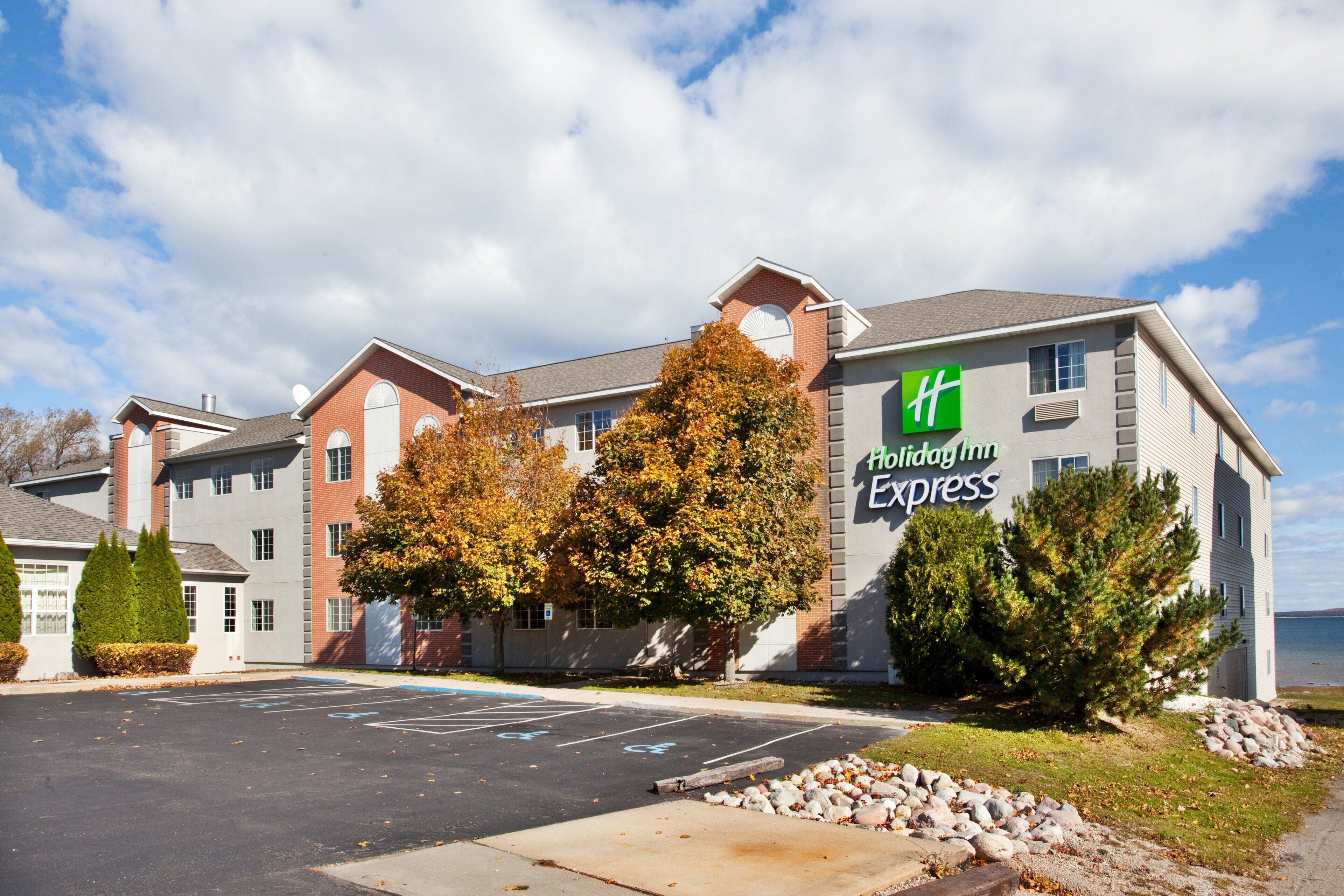 Un hôtel Holiday Inn Express doté d’un parking et entouré d’un paysage aux couleurs automnales.