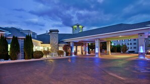 A hotel with a spacious parking lot, a prominent entrance with a covered area, and a stone facade.