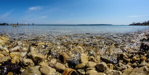 A rocky shoreline with clear water and a distant lighthouse. - Holiday Inn Express St. Ignace-Lake Front by IHG (St Ignace)
