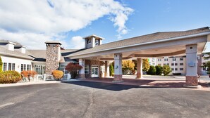 A hotel with a covered parking area, stone facade, and a clear sky. - Holiday Inn Express St. Ignace-Lake Front by IHG (St Ignace)