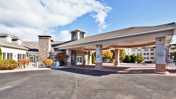 A hotel with a covered parking area, stone facade, and a clear sky.