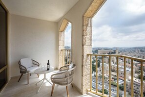 Ein Balkon mit Korbstühlen, einem kleinen Tisch und einer Flasche.