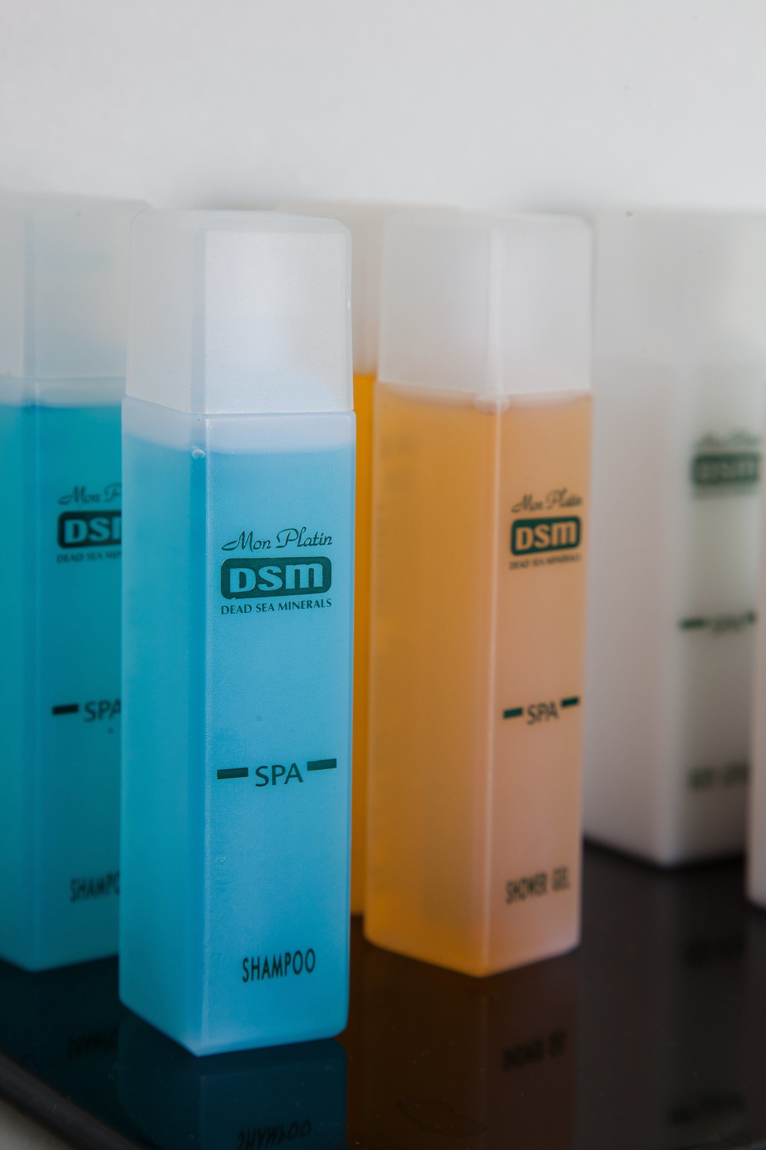 A row of shampoo bottles labeled 'Mon Platinum DSTM' and 'Spa' on a reflective surface.