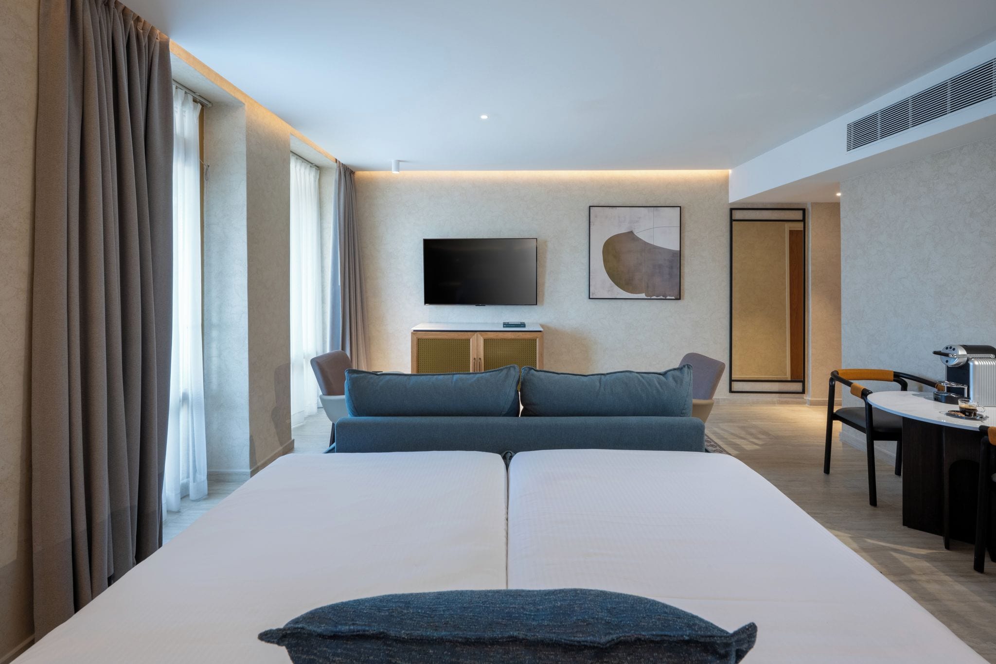 Una habitación de hotel con una cama grande, una televisión de pantalla plana, un escritorio y una silla.