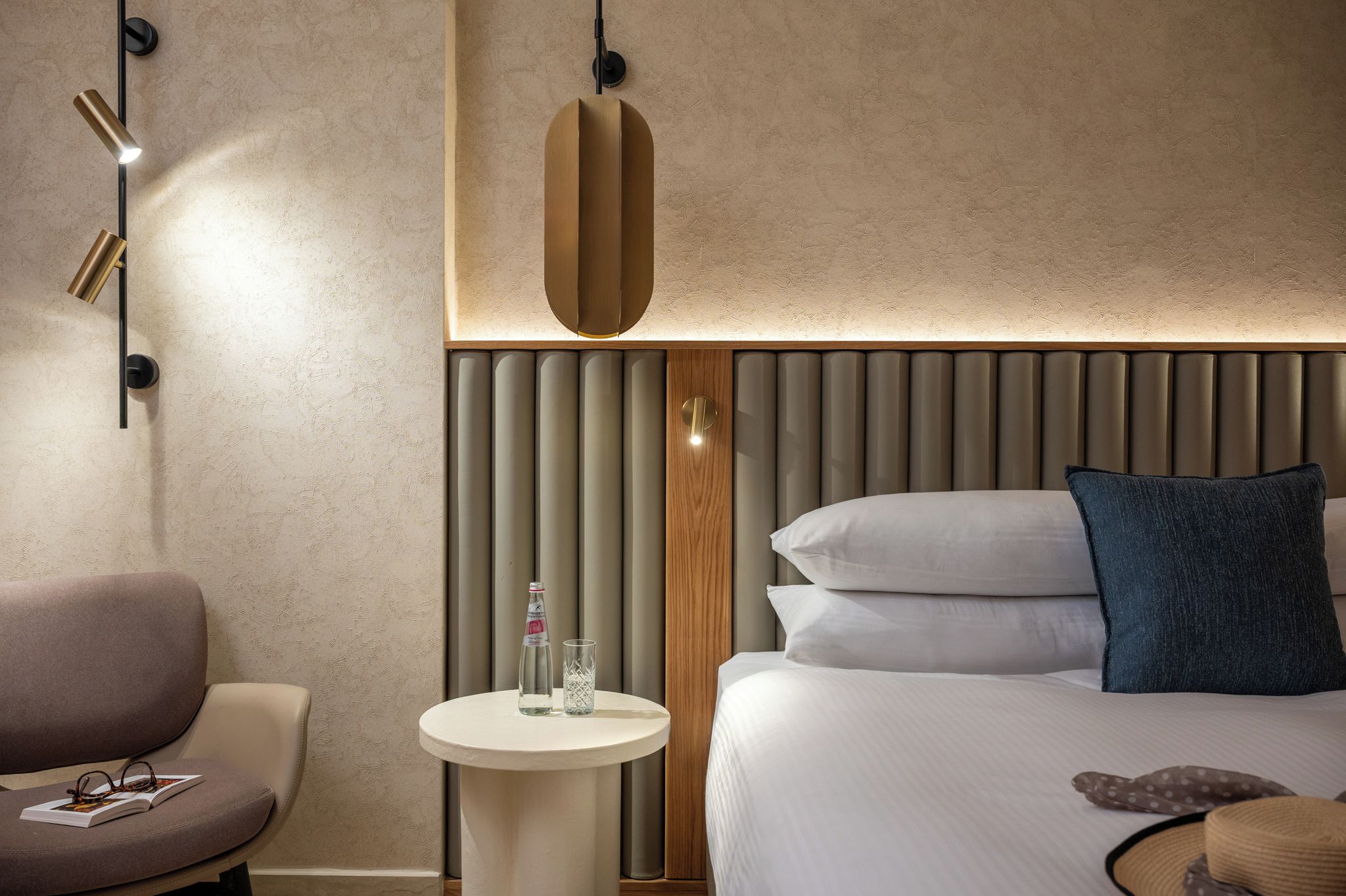 A modern hotel room with a bed, bedside table, and a chair.