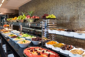 Un bufé con diversos alimentos, entre ellos frutas, verduras y carnes.