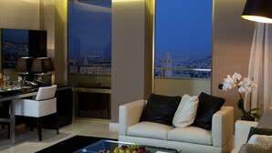 Una sala de estar moderna con vista a la ciudad, un comedor y un sofá con almohadones decorativos.