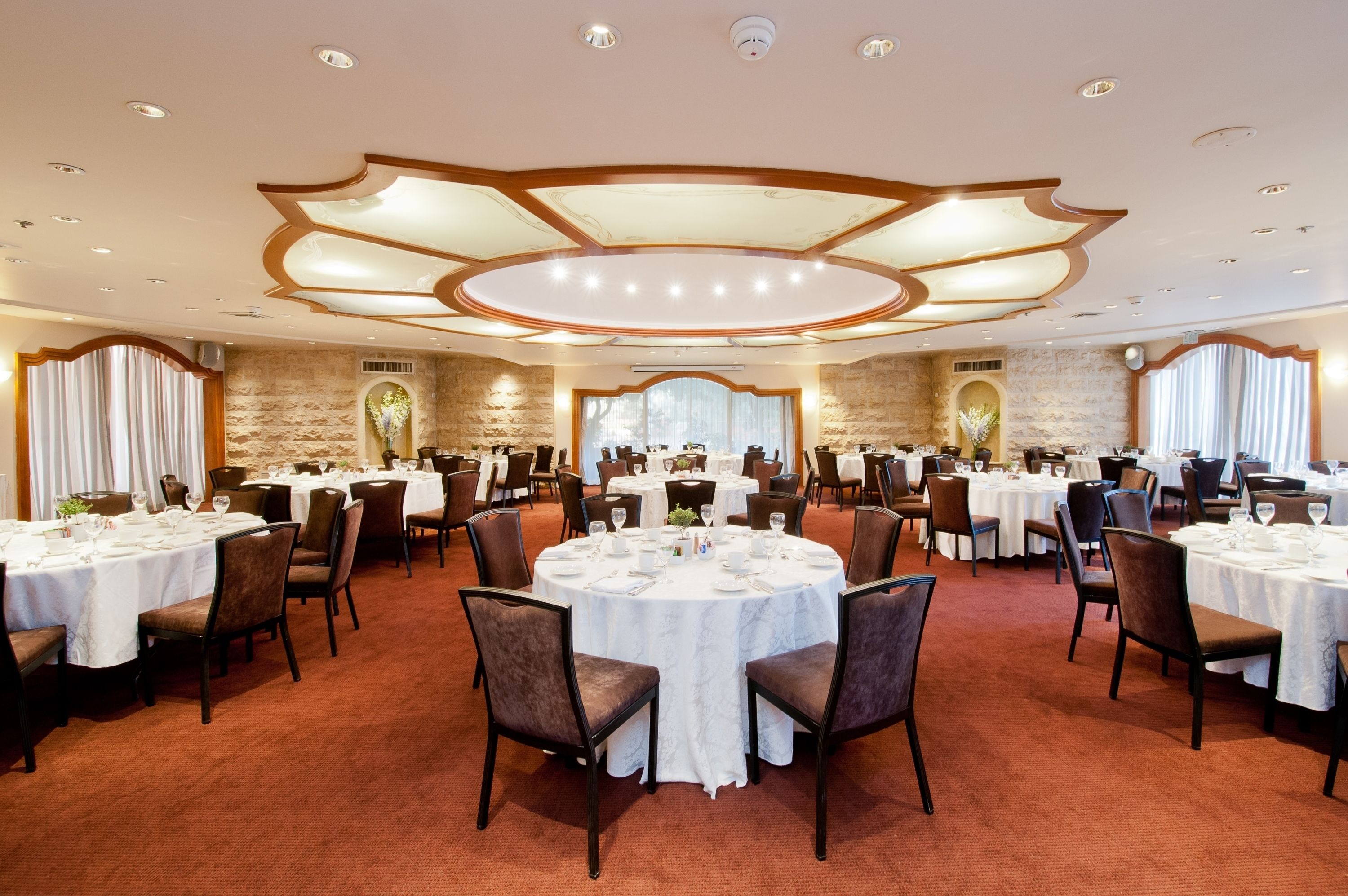 A banquet hall with round tables, chairs, and a decorative ceiling.