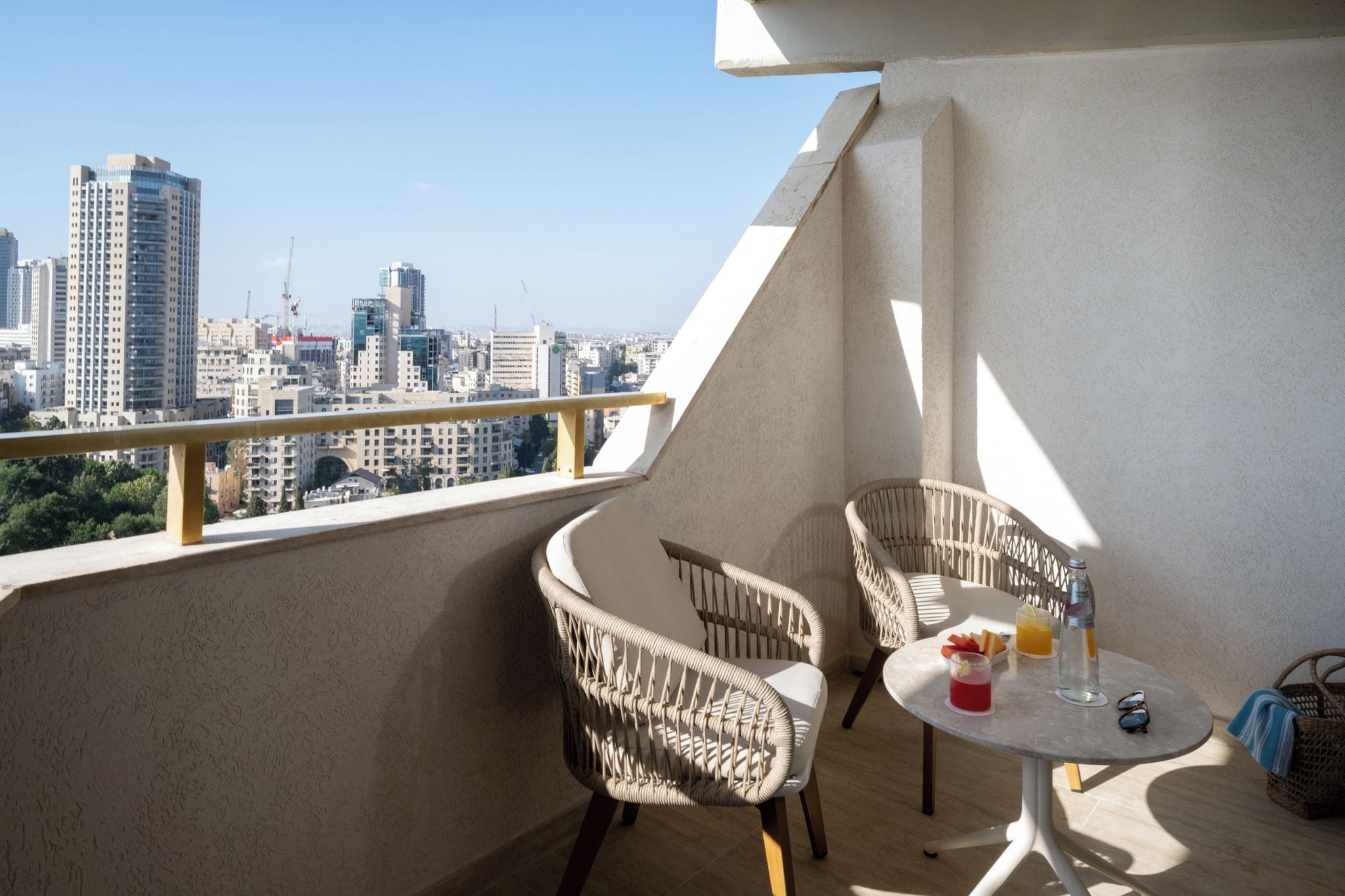 Ein Balkon mit Korbstühlen, einem Tisch und Blick auf die Stadt.