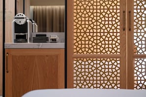 Un mueble de madera con una cafetera, una taza de café y una puerta mosquitera estampada.