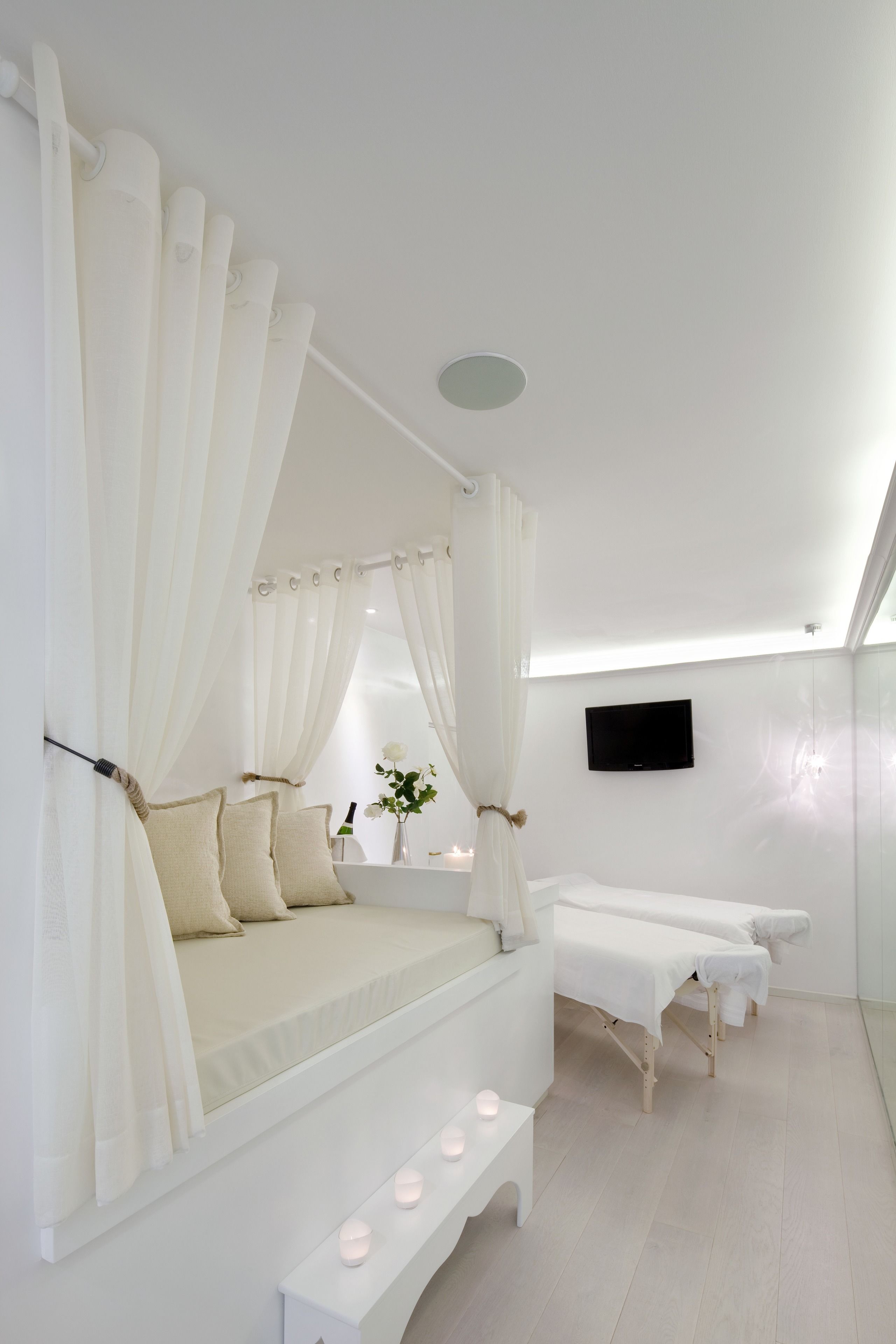 A modern bedroom with a canopy bed, a vanity with a mirror, and a television on the wall.