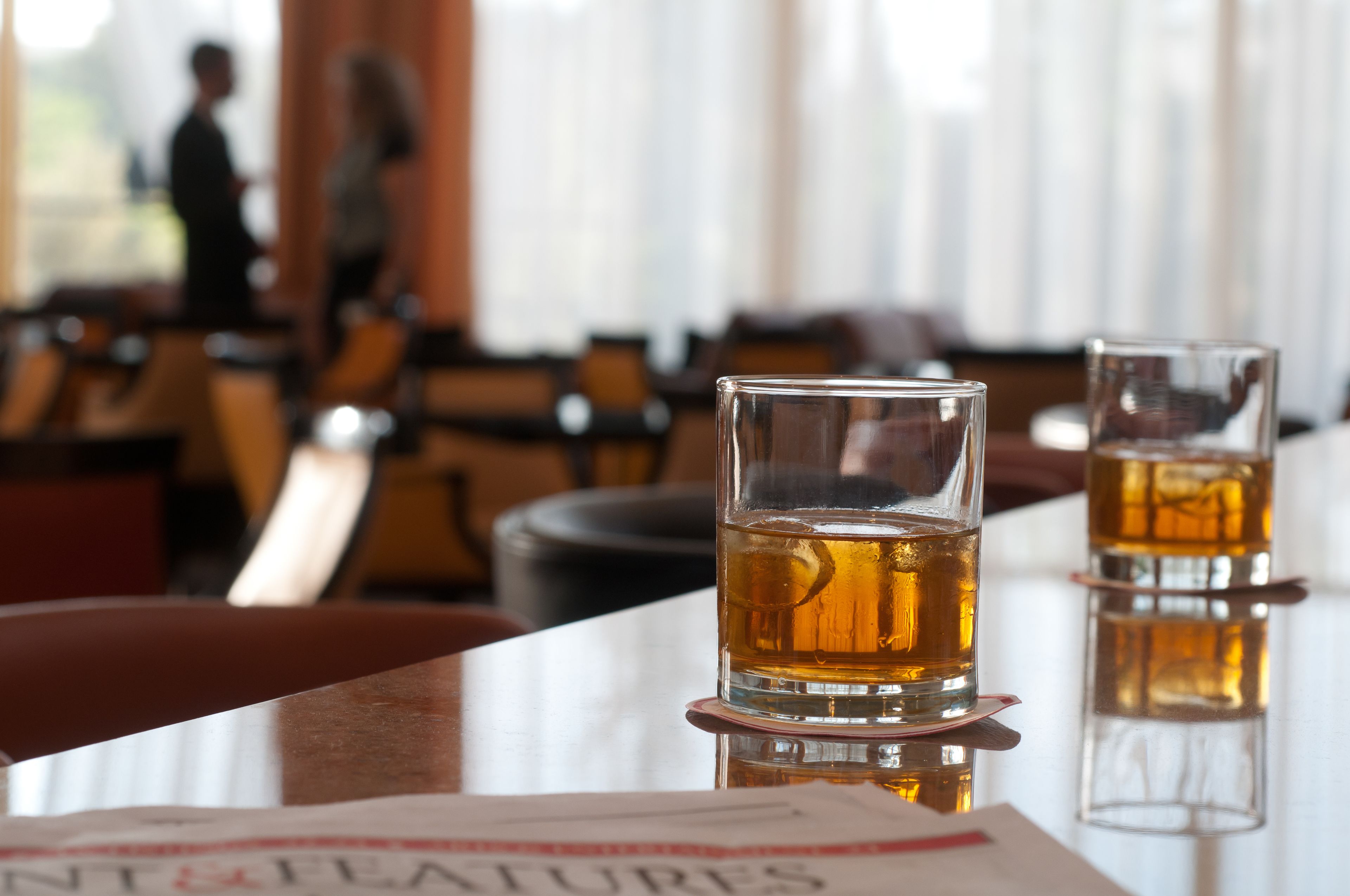 Two glasses of amber liquid on a reflective surface with a book titled "NIGHTFLIGHTS" in the foreground.